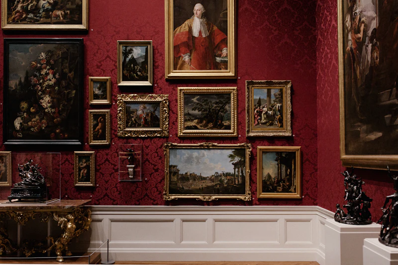 Salle de musée aux murs rouges couverts de tableaux
